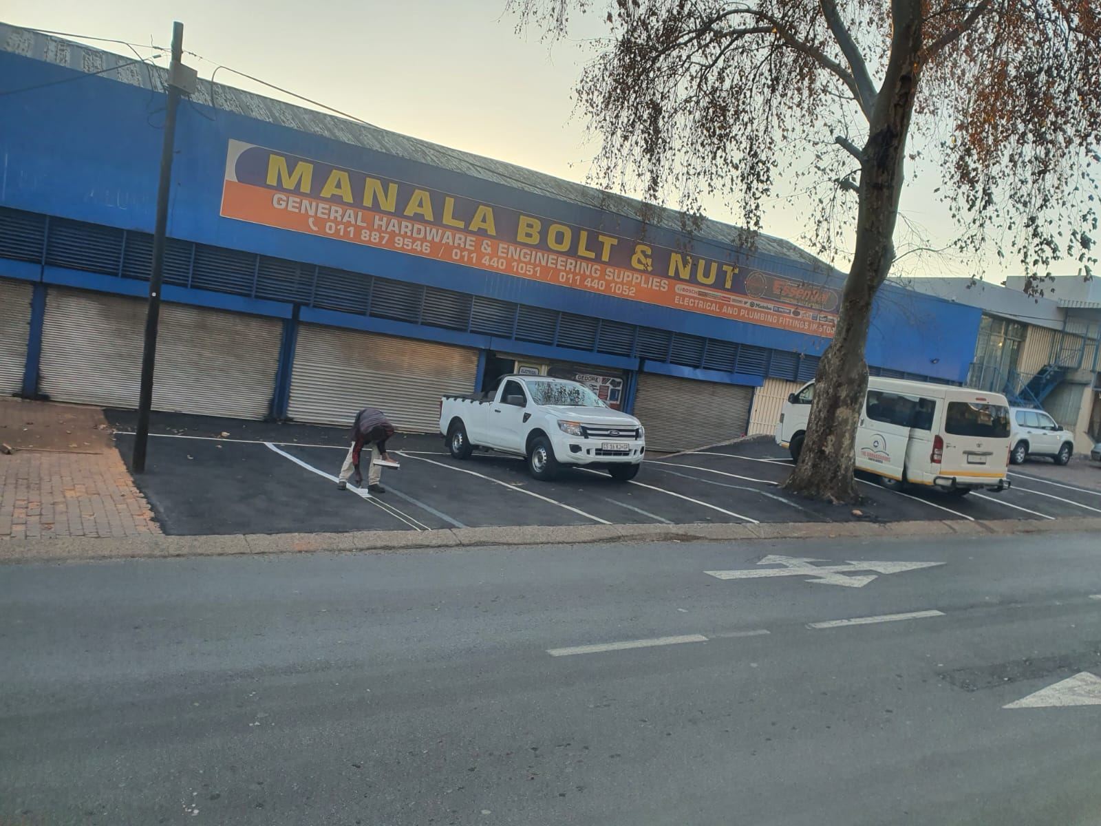 Worker painting parking bay lines outside a hardware store