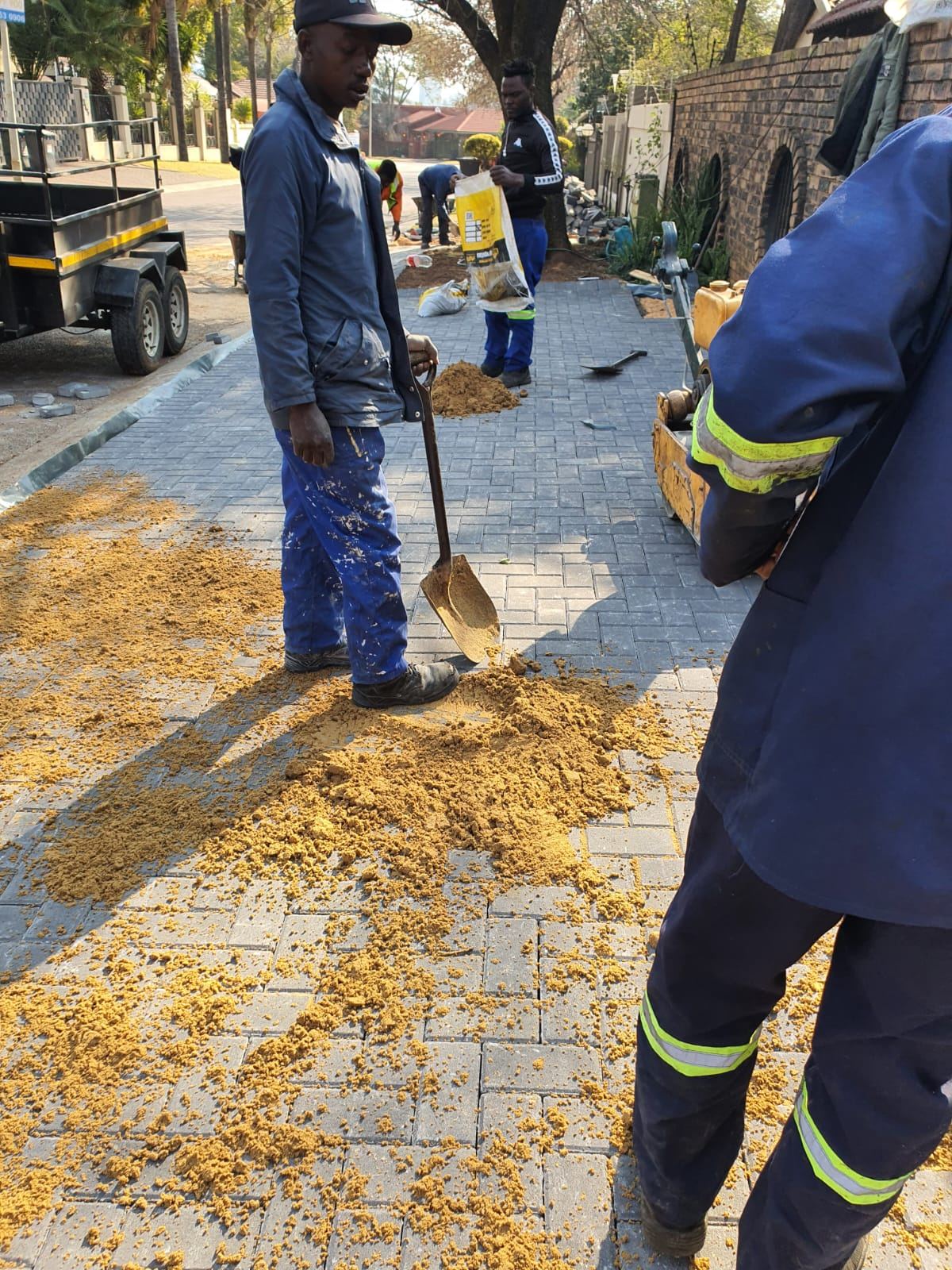 Workers sweeping sand into block paving joints