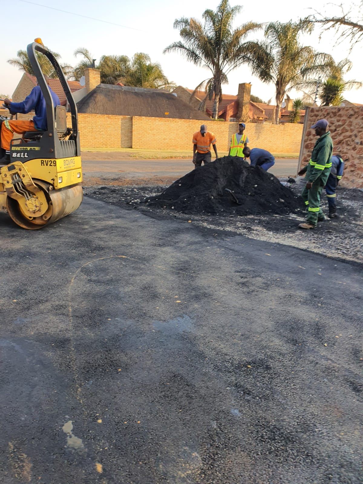 Excavator preparing base for tar surfacing
